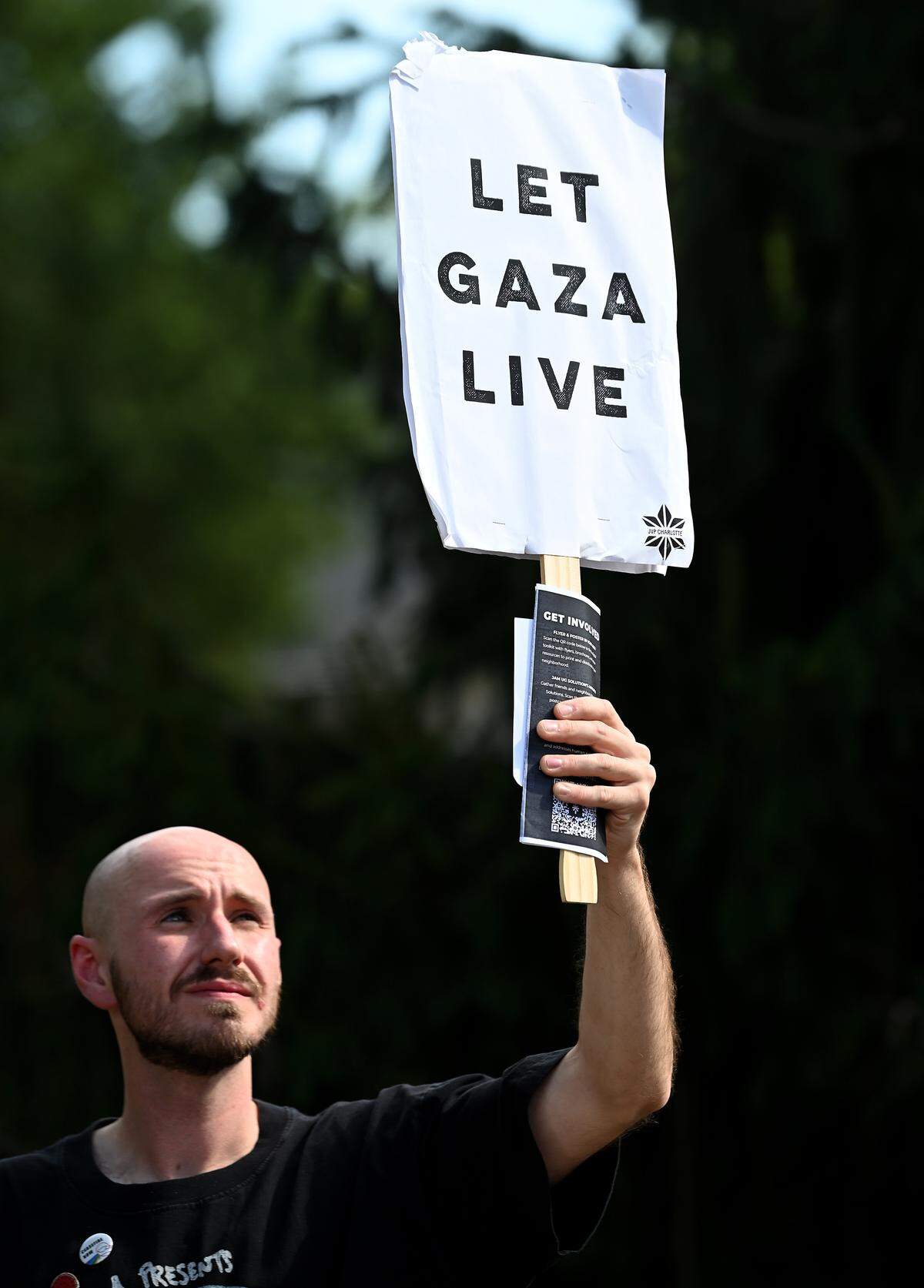 Tyler Crawford glances up toward his “Let Gaza Live” sign during a “Bread Not Bullets” rally in Davidson, NC on Monday.