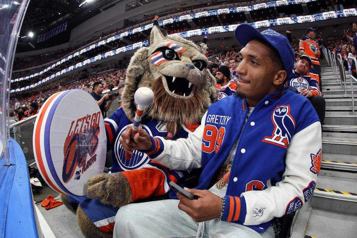 EDMONTON, CANADA - JUNE 06: NFL running back Chuba Hubbard and the Edmonton Oilers mascot interact during the second overtime period between the Florida Panthers and the Edmonton Oilers in Game Two of the 2025 Stanley Cup Final at Rogers Place on June 06, 2025 in Edmonton, Alberta, Canada. (Photo by Steph Chambers/Getty Images)