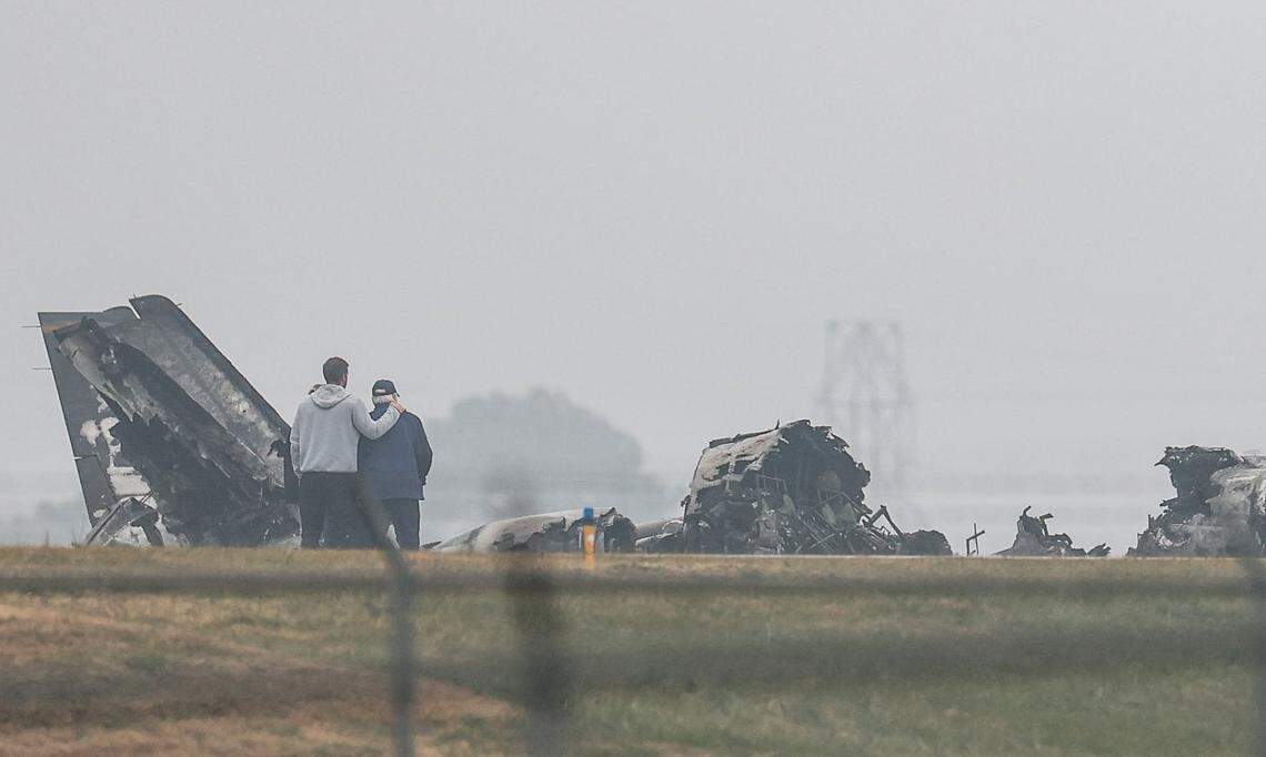 People comfort each other as they observe wreckage from the crashed plane on Dec. 18, 2025, at Statesville Regional Airport.
