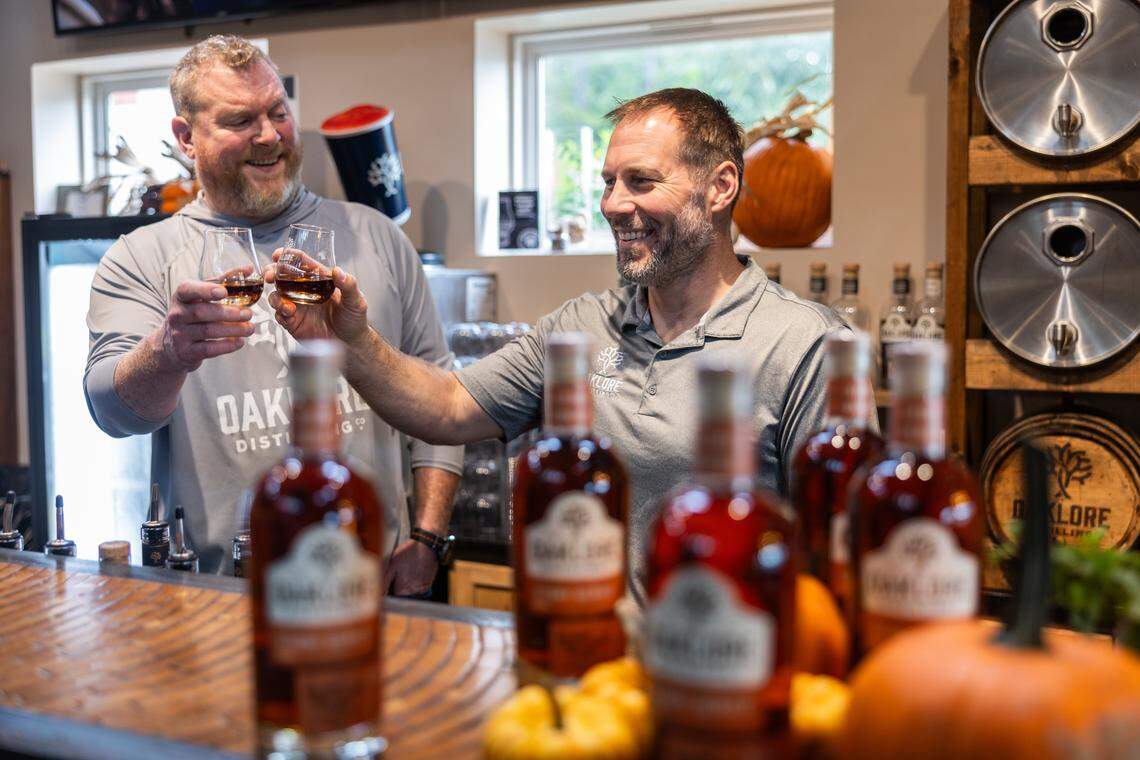 Matt Simpkins, left, and Tom Bogan cheers before sampling a whiskey at Oaklore Distilling Co. in Matthews, N.C., on Tuesday, September 30, 2025.