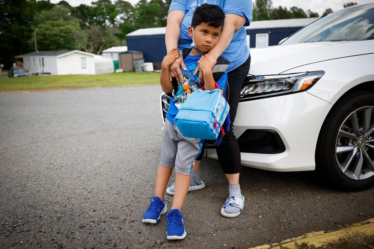 Ismael Ruiz, 6, stands with his mother, who asked not to be identified, near the school bus stop in Queen’s Grant Mobile Home Park in Charlotte, on May 2, 2022.
