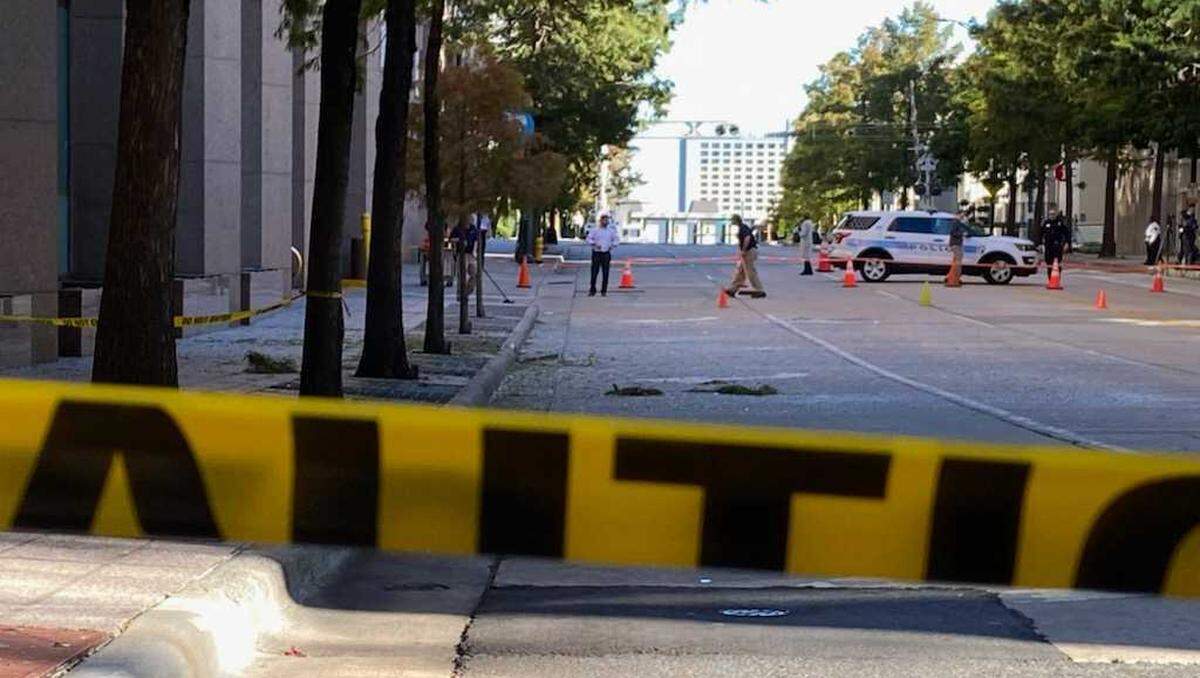 Workers clean up shattered glass on Martin Luther King Boulevard in uptown Charlotte after a bullet struck a 16th-floor window of One Wells Fargo Center, 301 S. College St., on Tuesday, Oct. 4, 2022.