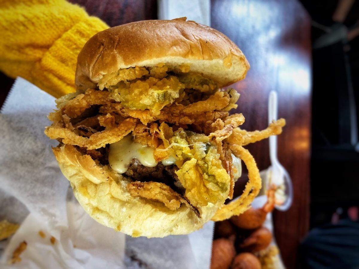Pinky’s White Trash Burger is piled with fried pickles, fried onion straws and spicy ranch.