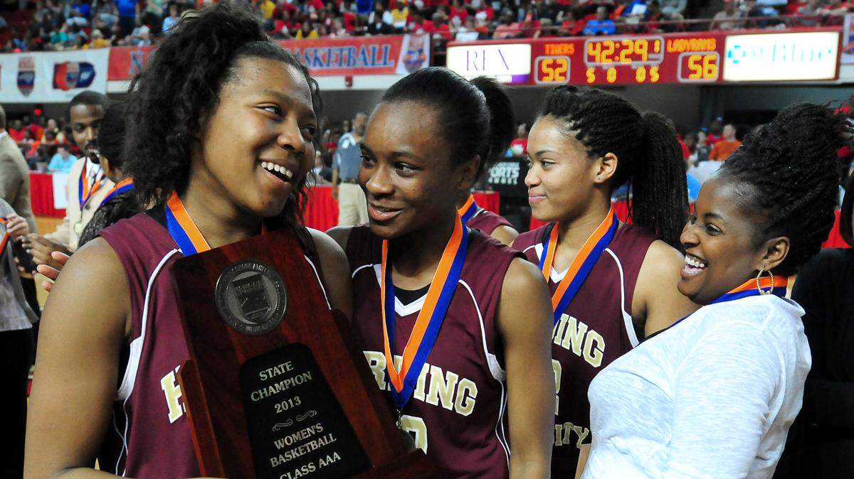 Harding University’s (24) Keousha Griffin carries the team’s championship trophy as they celebrate their 56-52 victory over Chapel Hill in girls N.C. 3A State Championship game at Reynolds Coliseum on the campus of North Carolina State on Saturday, March 16, 2013. Jeff Siner - jsiner@charlotteobserver.com