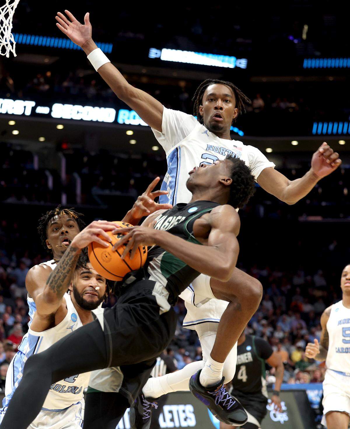 UNC Tar Heels (L-R) Harrison Ingram, RJ Davis and Jae’Lyn Withers make the stop on Wagner’s Melvin Council Jr., center, on a drive to the basket during first-half action at Spectrum Center in Charlotte, NC on Thursday, March 21, 2024. The Tar Heels battled Wagner in the first Round of the 2024 NCAA Division 1 Men’s Basketball Championship at Spectrum Center in Charlotte, NC on Thursday, March 21, 2024, with UNC winning, 90-62.