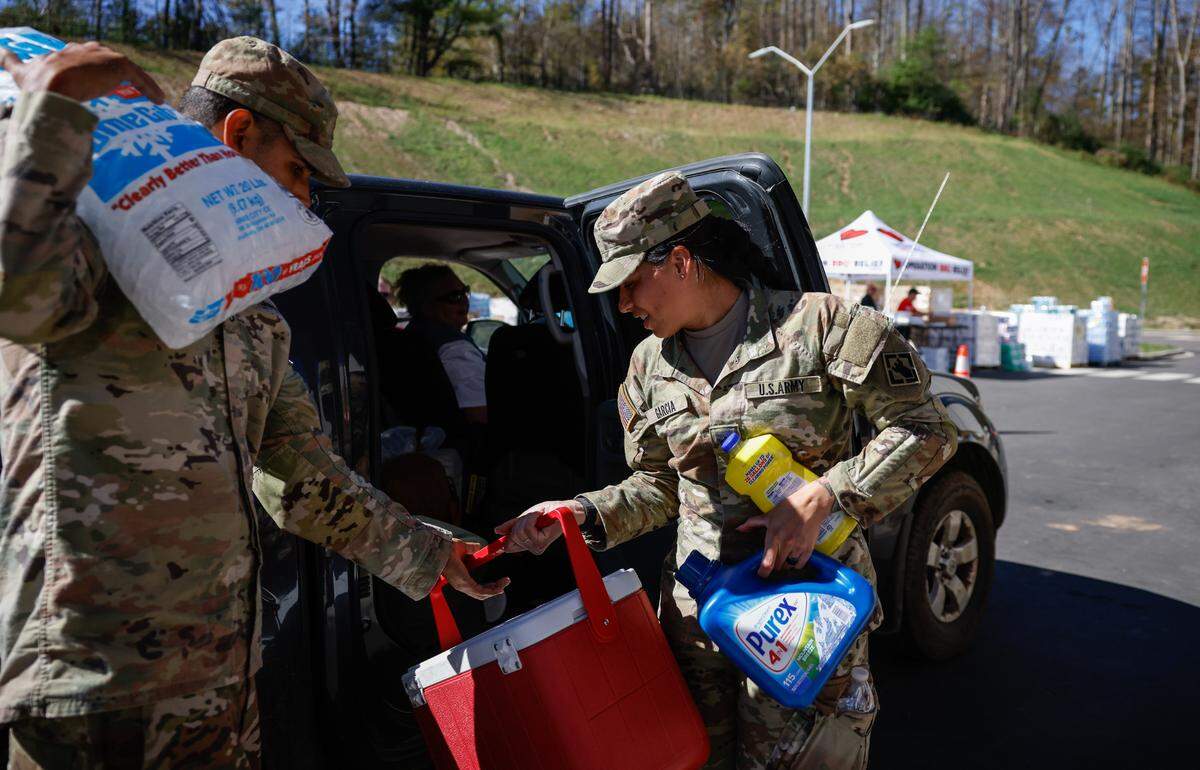 Active-duty soldiers from Fort Liberty place ice and cleaning supplies into the car of a resident affected by Hurricane Helene at Mitchell Elementary/Middle School in Bakersville on Wednesday, Oct. 9, 2024.