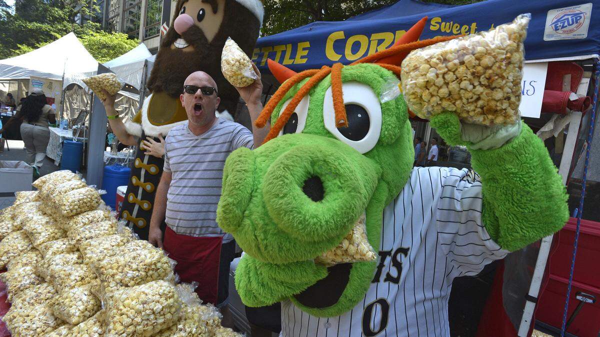 Charlotte Knights mascot Homer the Dragon stopped by to help Scott Volk sell kettle corn at the Cousins Kettle Corn tent at 2014’s Taste of Charlotte.