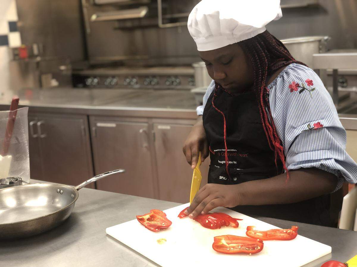 A student from Druid HIlls Academy chops red bell pepper for a fajita dish.