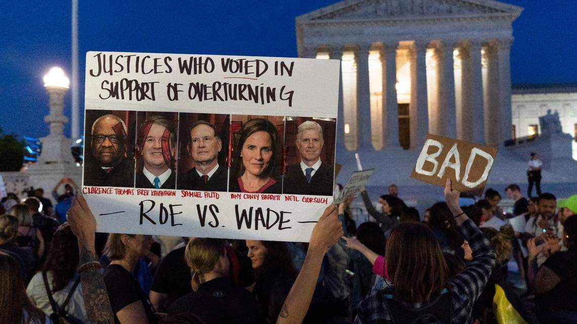 Nikki Tran of Washington, holds up a sign with pictures of Supreme Court Justices Clarence Thomas, Brett Kavanaugh, Samuel Alito, Amy Coney Barrett, and Neil Gorsuch, as demonstrators protest outside of the U.S. Supreme Court on May 3, 2022.