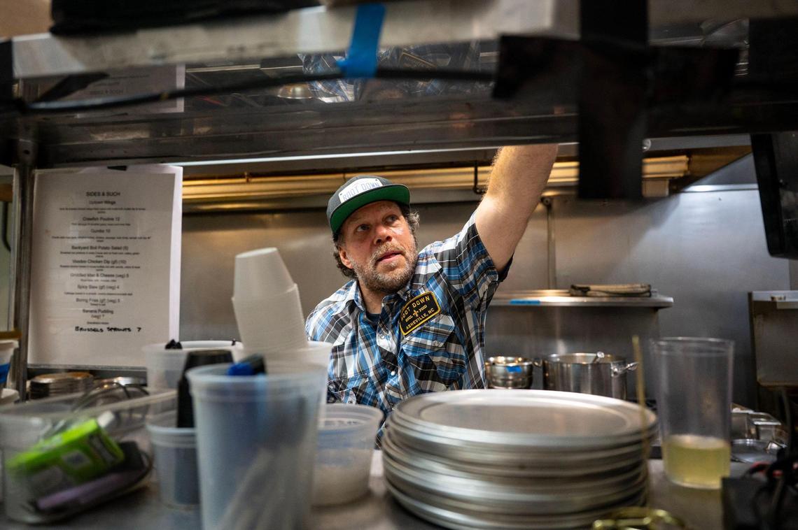 Chef Dano Holcomb reaches for a to-go box while filling an order at the Root Down Kitchen inside Terra Nova Beer Co. in Swannanoa, N.C., Friday, June 27, 2025. Root Down Kitchen was formerly a food truck at The Salvage Station in Asheville before Hurricane Helene destroyed it, prompting Holcomb and his kitchen to relocate to Terra Nova Beer Co. for their current collaboration.
