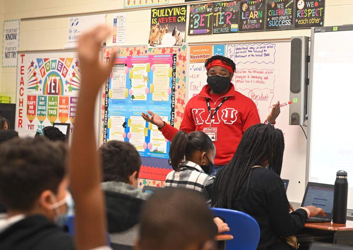 Charlotte-Mecklenburg Schools is facing a crunch with teacher and other staff absences as COVID-19 cases again surge. In this photo, 5th grader teacher Tyler Adams talks with his class at Newell Elementary School in Charlotte.