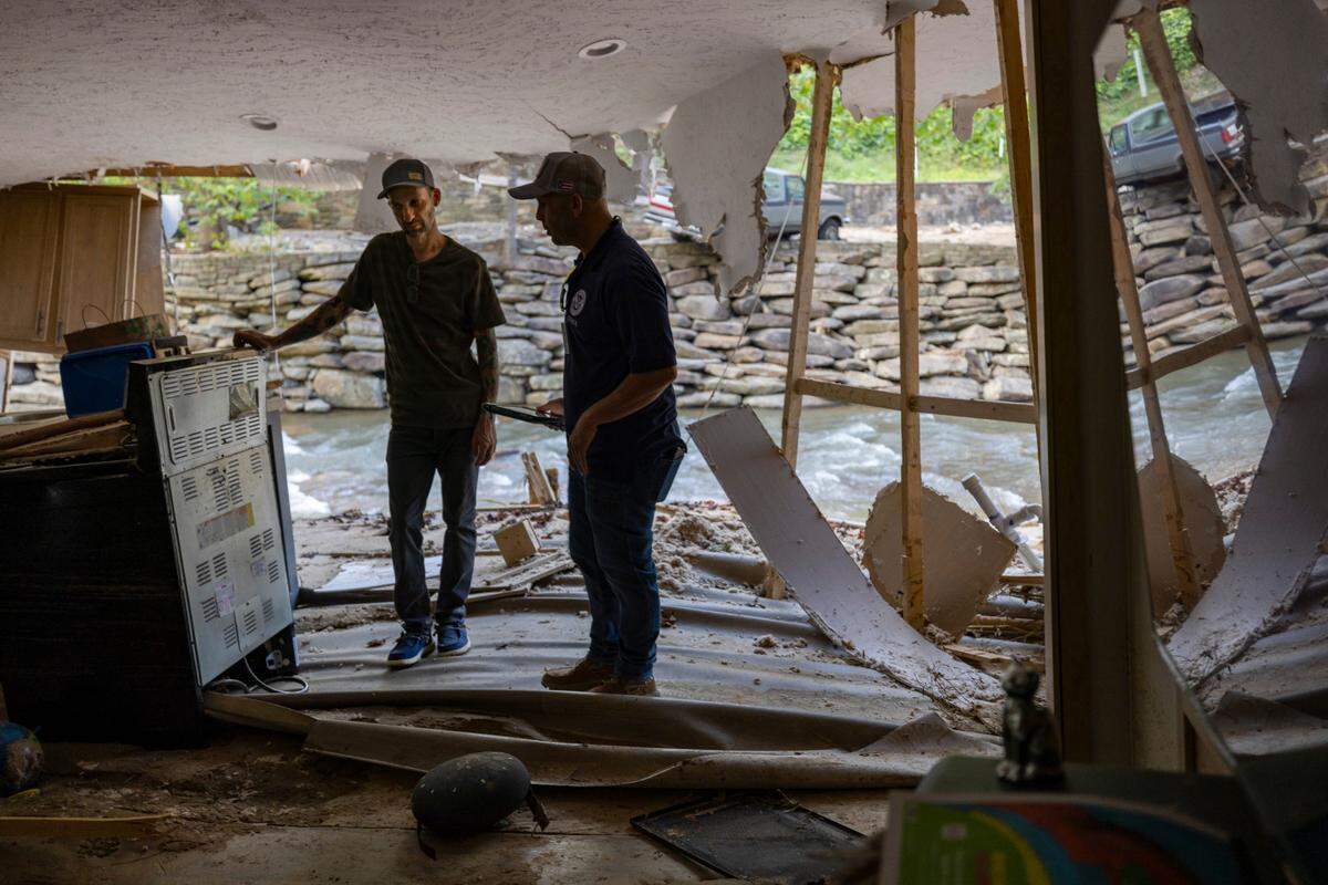 FEMA employee Jirau Alvaro talks with Danny Mancini Sunday at Mancini’s Buncombe County home. Less than a week after the flood, the federal government awarded Mancini $54,000 for his losses.