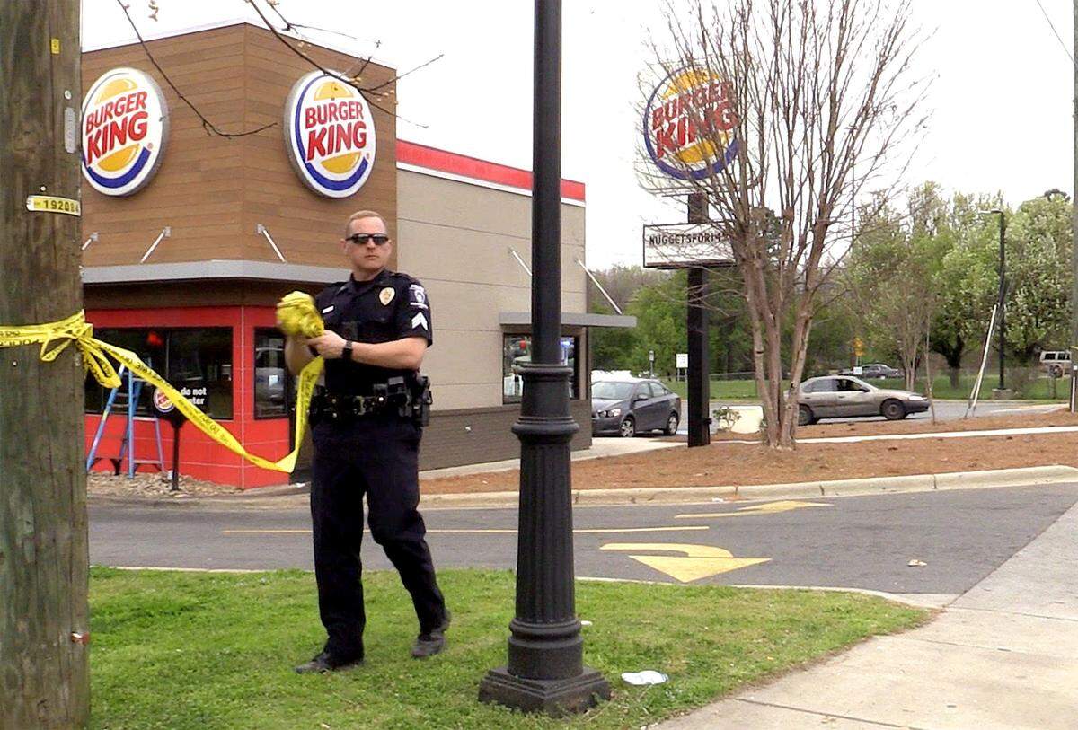 A Charlotte-Mecklenburg police officer gathers up tape outside the Burger King on Beatties Ford Road near Interstate 85 in Charlotte on March 25, after a man who was allegedly armed was shot and killed by an officer.