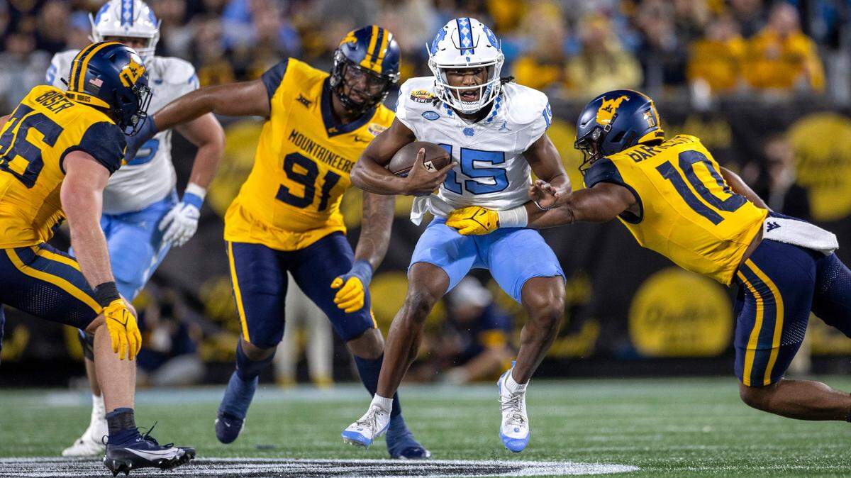 North Carolina quarterback Conner Harrell (15) looks for running room on a 15-yard carry in the first quarter against West Virginia’s Jared Bartlett (10) on Wednesday, December 27, 2023 at Bank of American Stadium in Charlotte, N.C.