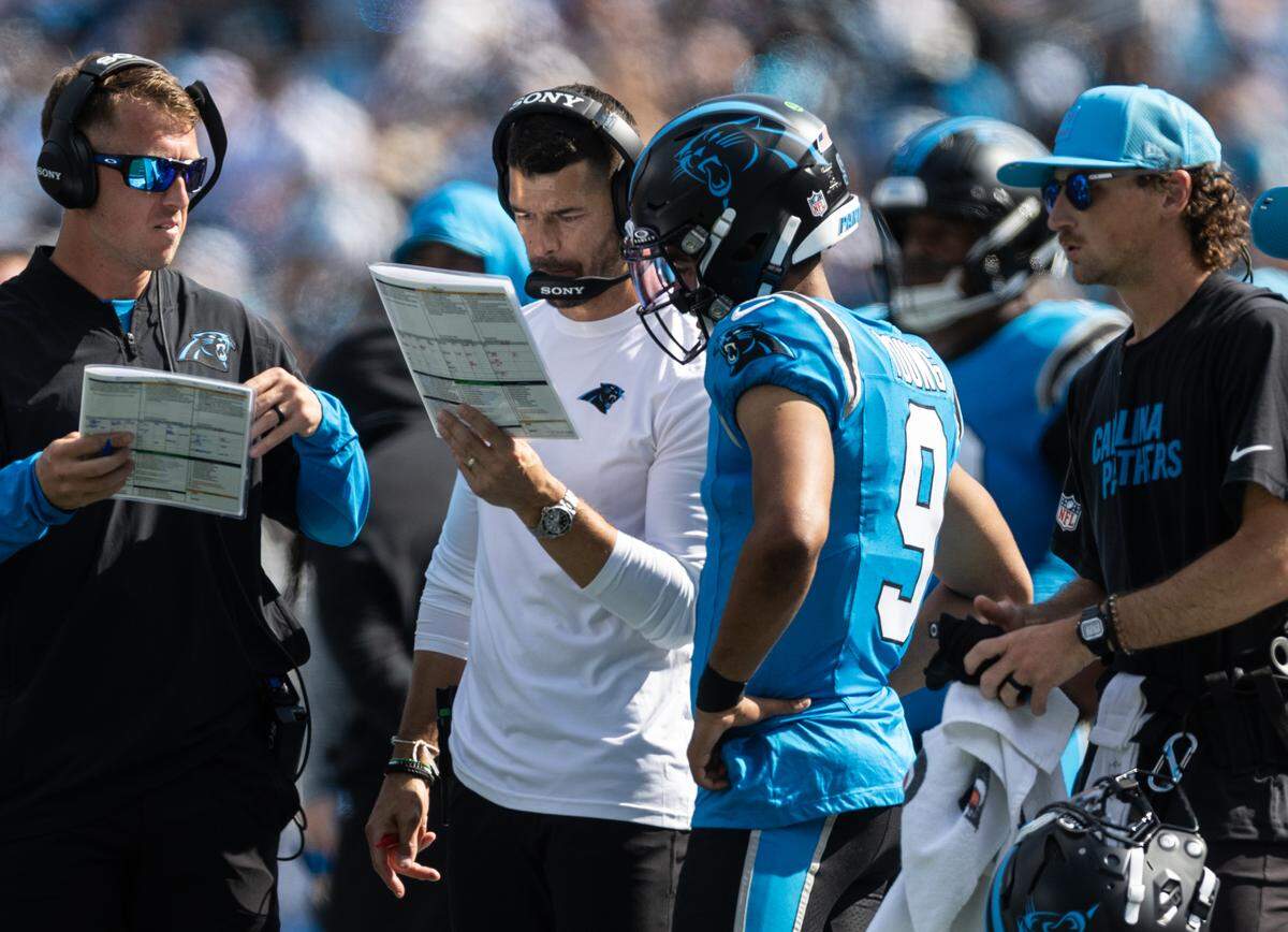 Carolina Panthers coach Dave Canales, left, speaks to Carolina Panthers quarterback Bryce Young on Sept. 21, 2025, at Bank of America Stadium.