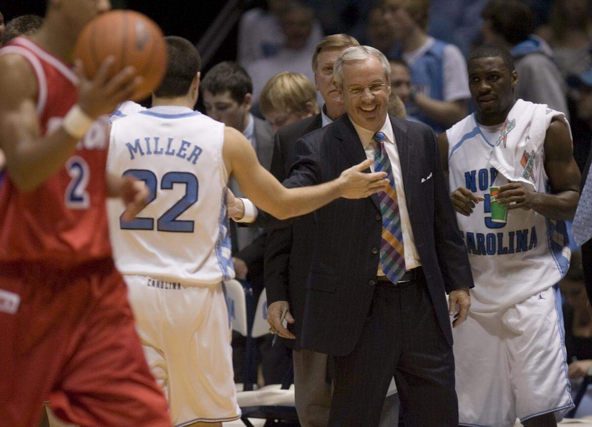 UNC head coach Roy Williams cracks a smile after congratulating Wes Miller (22) for chasing down a loose ball on Dec. 31, 2006, in the Smith Center. 