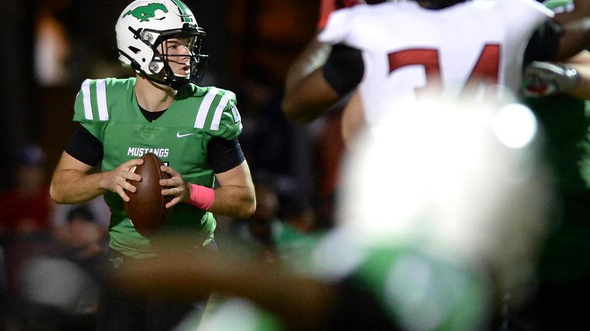 Myers Park Mustangs quarterback Lucas Lenhoff, left, drops back to pass as the South Meck Sabres defense rushes during second quarter action on Friday, October 22, 2021 at Myers Park High School.