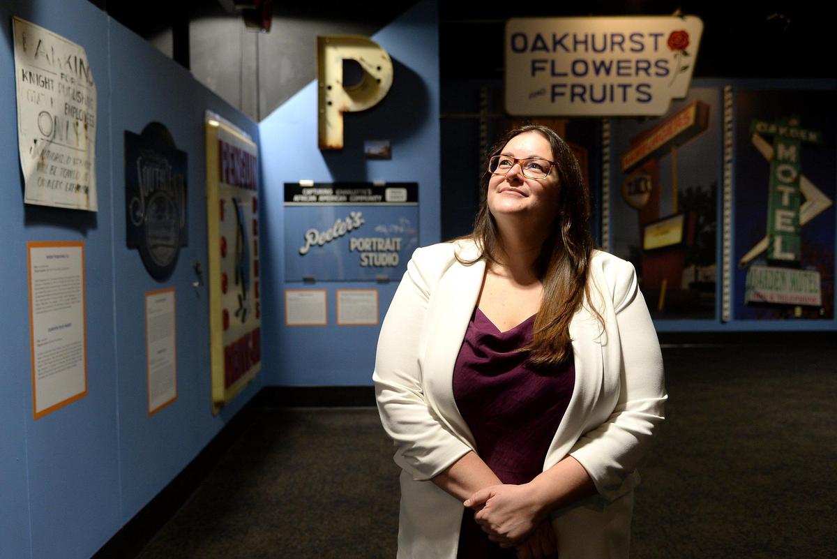 Adria Focht stands in the “Charlotte: Signs of Home” exhibit at the Charlotte Museum of History on Monday, December 6, 2021. Focht is resigning as museum president and CEO after four years. Her resignation is effective Dec. 31.