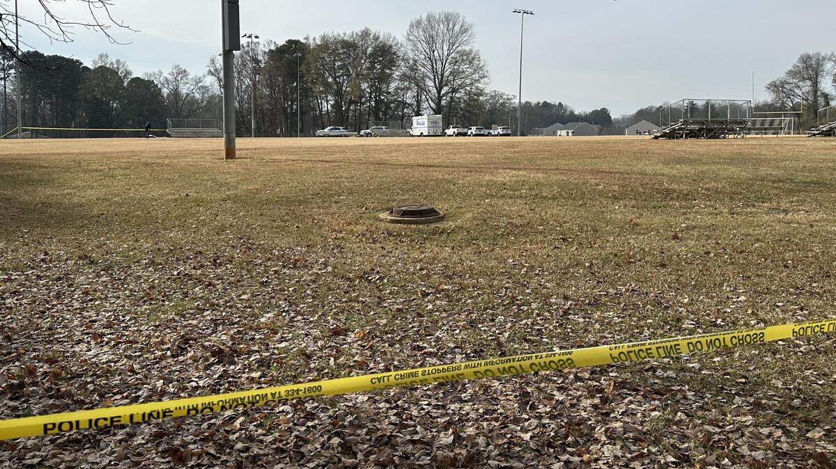 Police vehicles parked near a football field at a west Charlotte park in the 4800 block of Tuckaseegee Road, where a person was found shot dead.