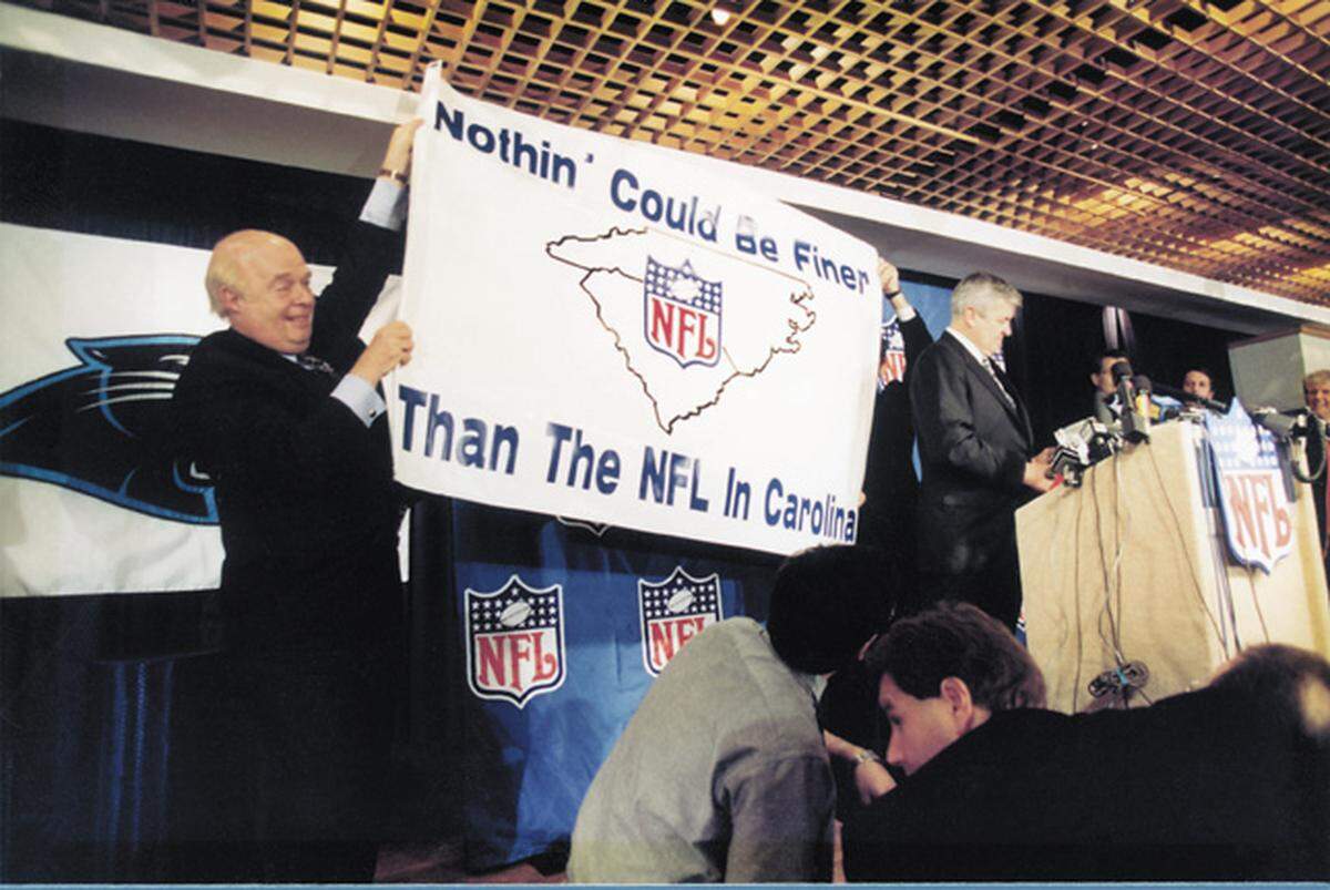 Sports marketer Max Muhleman (left) helps hold up a sign promoting the Carolina Panthers’ candidacy as an NFL franchise. Original Panthers owner Jerry Richardson is on the far right.