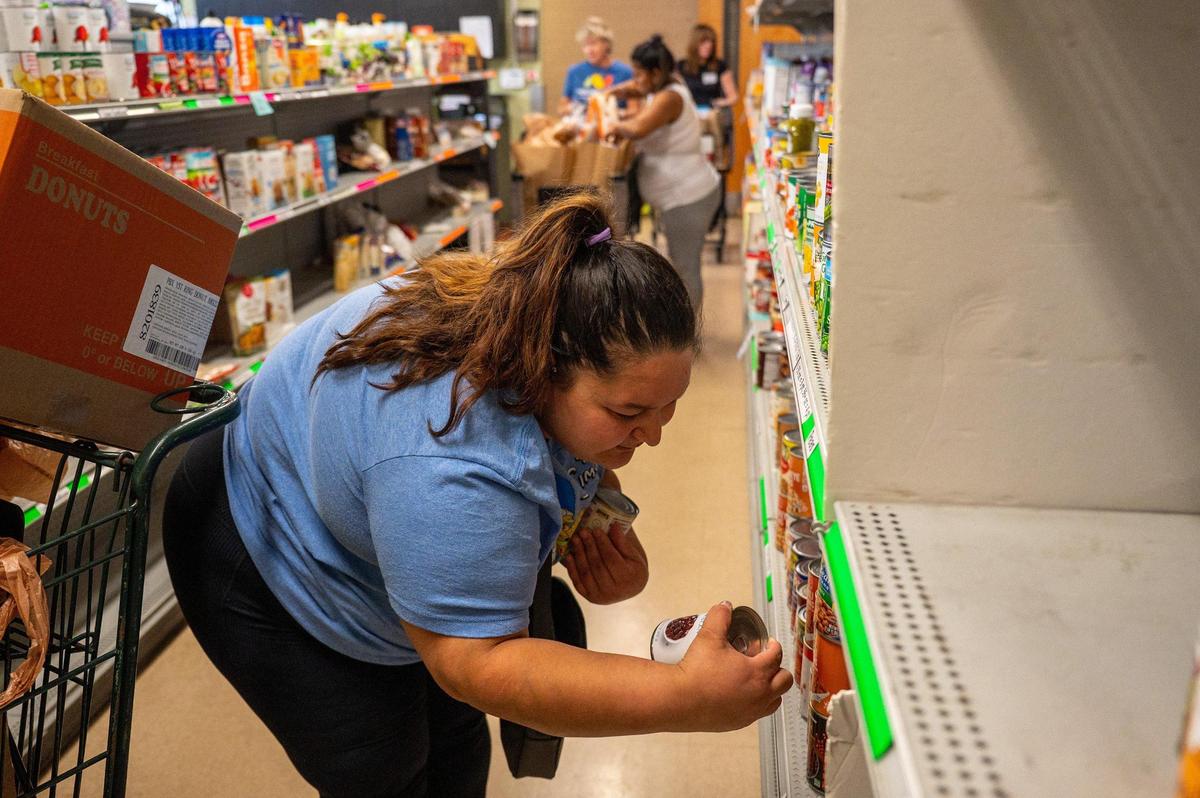 Patron Maria Rodriguez takes cans of beans off the shelf at the Ada Jenkins Center in Davidson, N.C., Thursday, June 12, 2025.