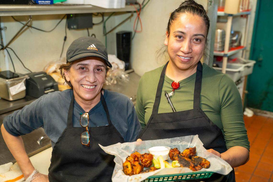 Moosehead Grill kitchen manager Eva Chavez and line cook Patty Mayorga hold up an order of hot wings.