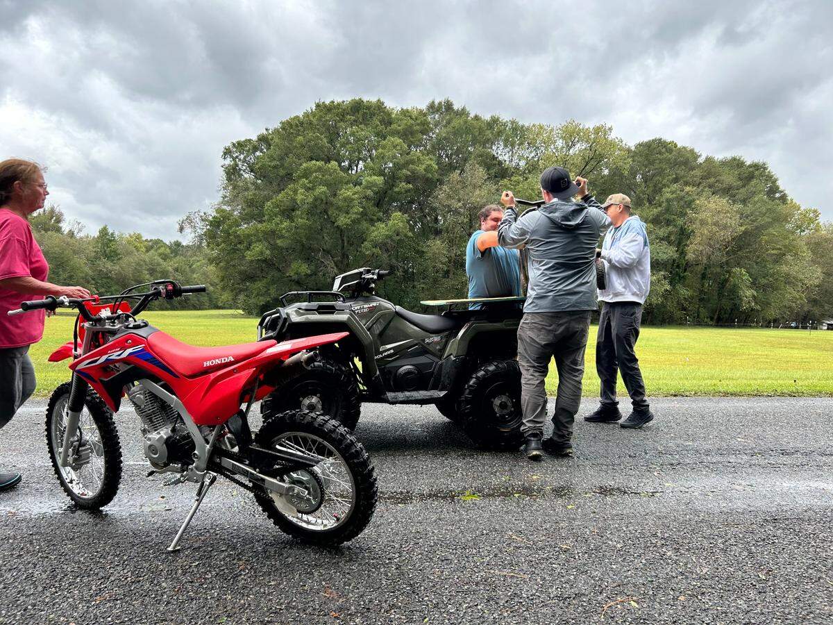 Residents load a generator on a ATV by Riverside Drive in Charlotte as water continued to rise Friday morning.