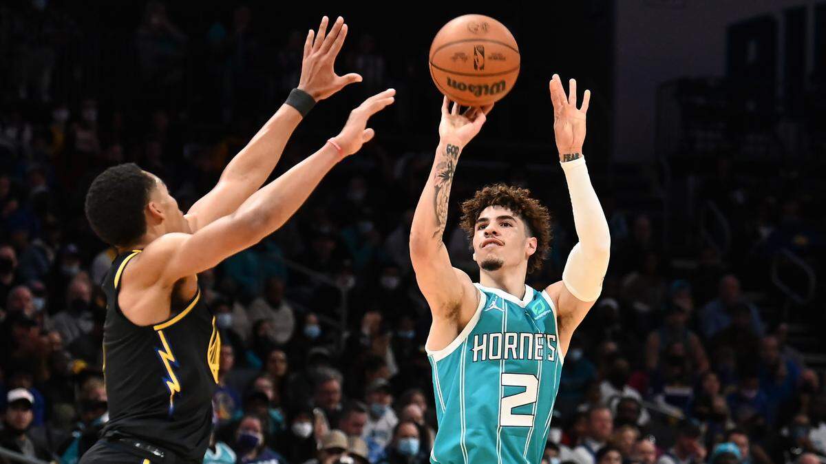 Charlotte Hornets guard LaMelo Ball, right, releases a three-point basket over Golden State Warriors guard Jordan Poole, left, during first half action at Spectrum Center in Charlotte, NC on Sunday, November 14, 2021.