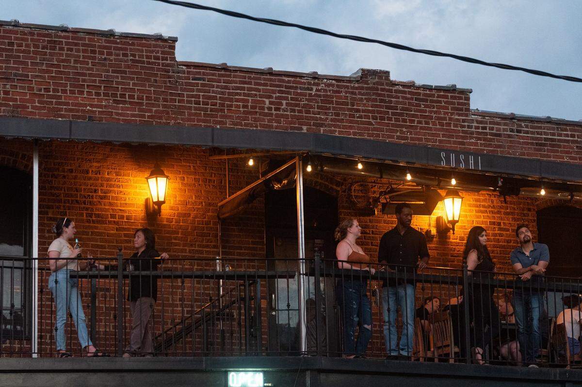 Patrons enjoy food and drinks on the second-floor exterior bar of Soul Gastrolounge in Plaza Midwood Monday evening, Aug. 8, 2022 in Charlotte, N.C.