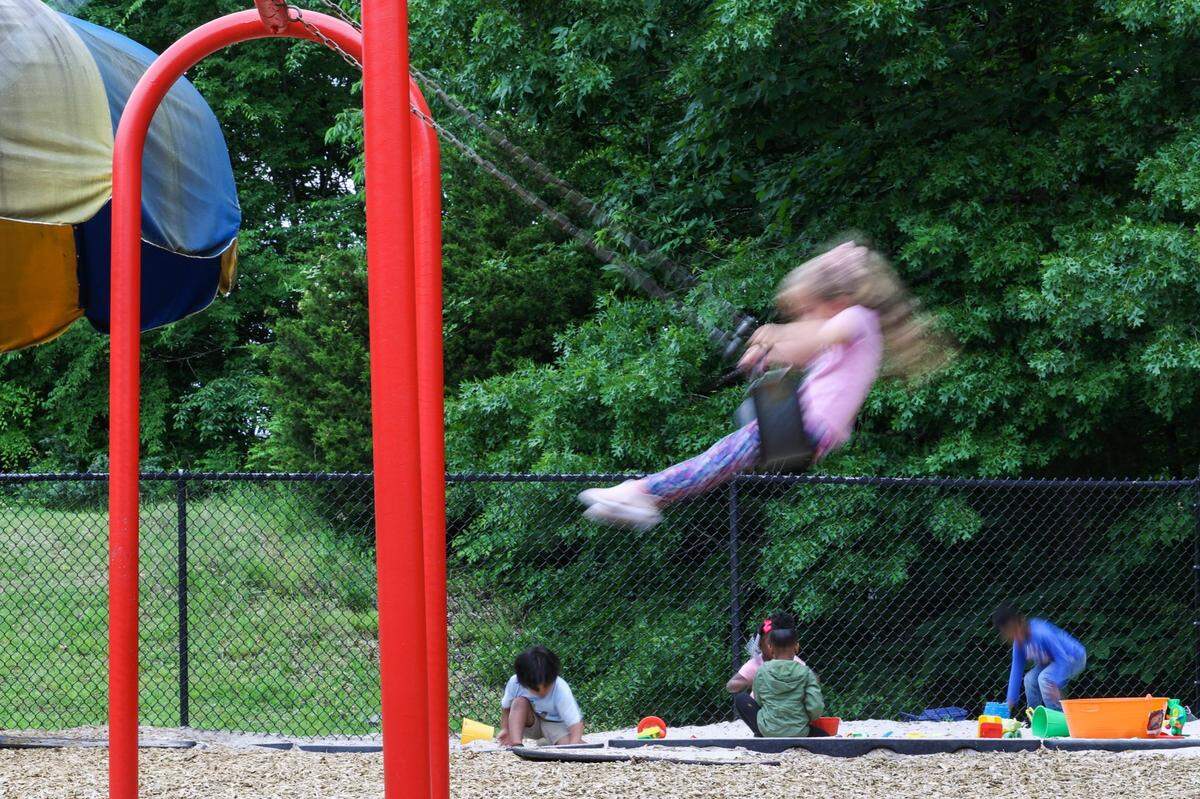 Kids enjoy the playground of Lollipops daycare center during outdoor time on Monday, April 10, 2023.