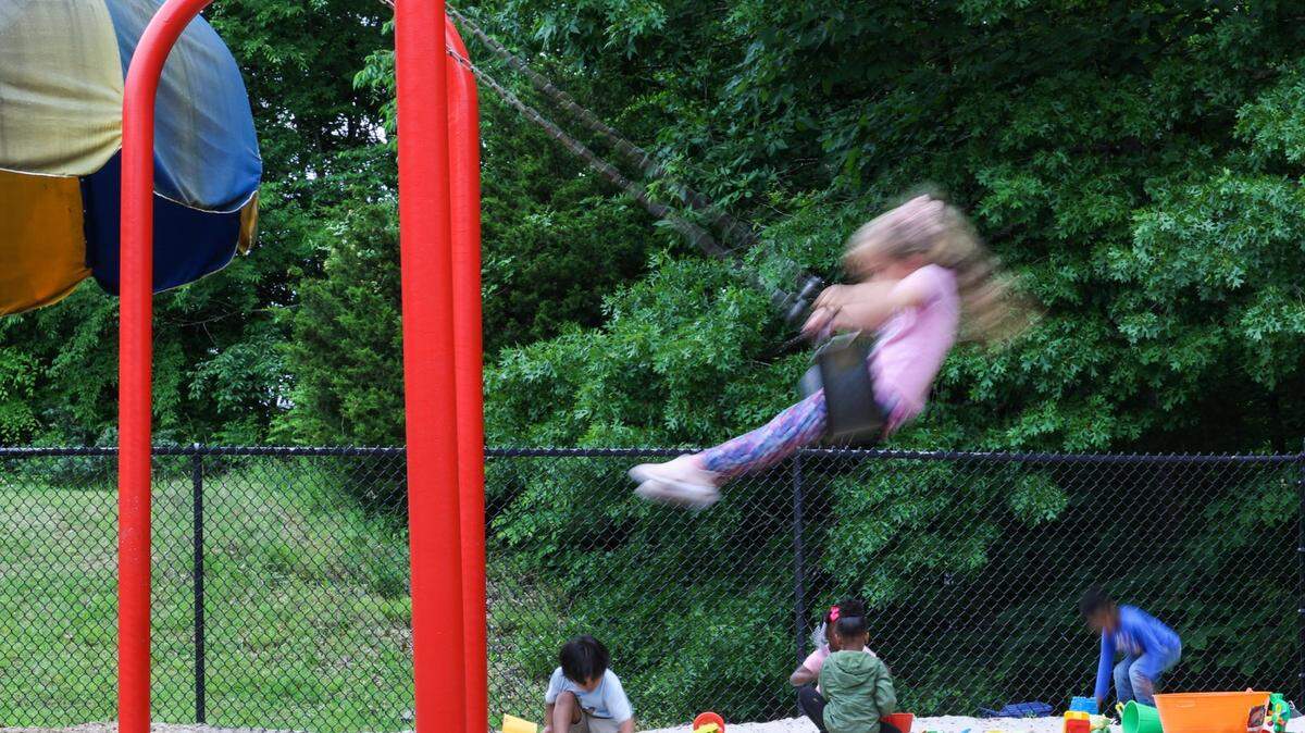 Kids enjoy the playground of Lollipops daycare center during outdoor time on Monday, April 10, 2023.
