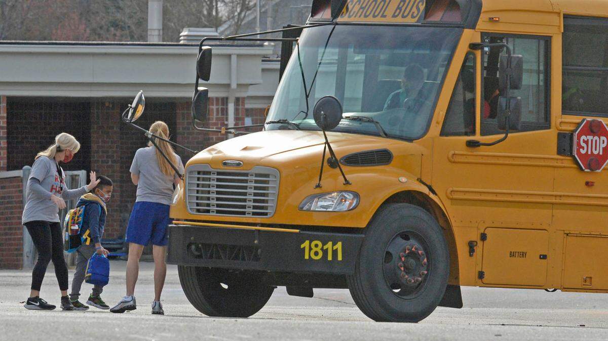 A teacher supervises students as they board a bus at the end of the day at Ballantyne Elementary School on Tuesday, March 9, 2021.