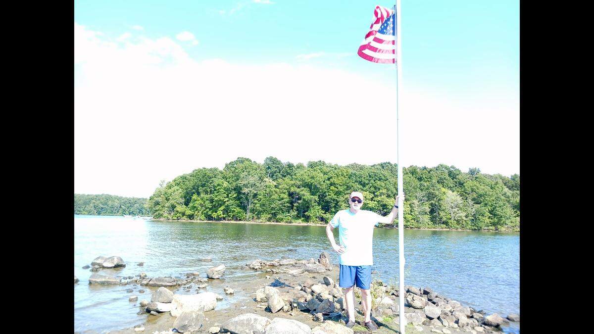 Longtime Lake Davidson resident Pat Jenkins poses in a shallow outcrop where someone erected a pole with the U.S. flag.