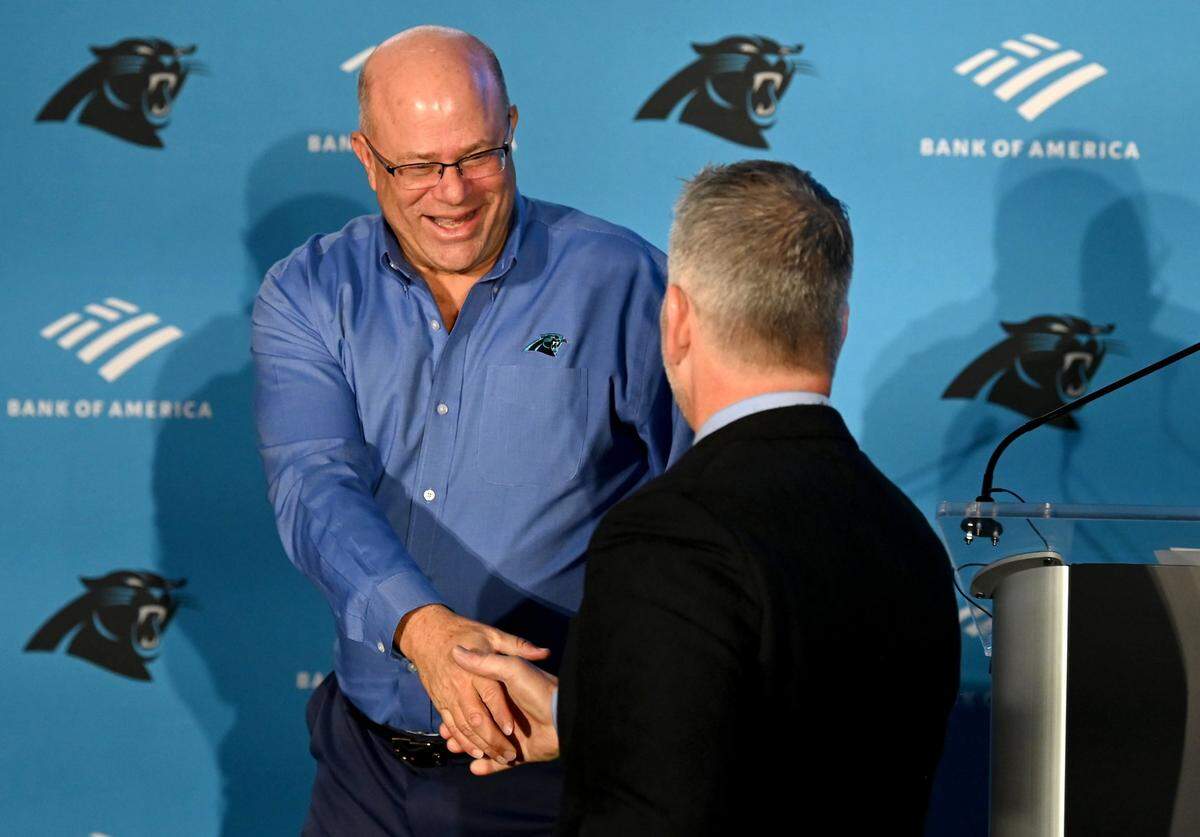 Carolina Panthers team owner David Tepper, left, shakes hands with new head coach Frank Reich, right, during Reich’s introductory press conference at Bank of America Stadium on Tuesday, January 31, 2023. Tepper would fire Reich 10 months later.