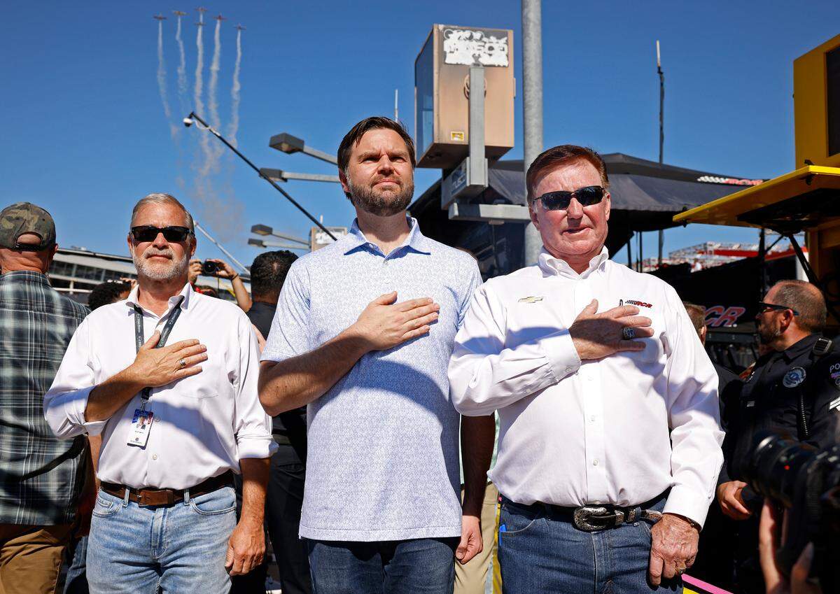 Scott Smith, left, Vice Presidential Nominee Senator JD Vance, center and NASCAR team owner Richard Childress, right, listen to the National Anthem prior to the running of the Bank of America Roval 400 at Charlotte Motor Speedway in Concord, NC on Sunday, October 13, 2024.