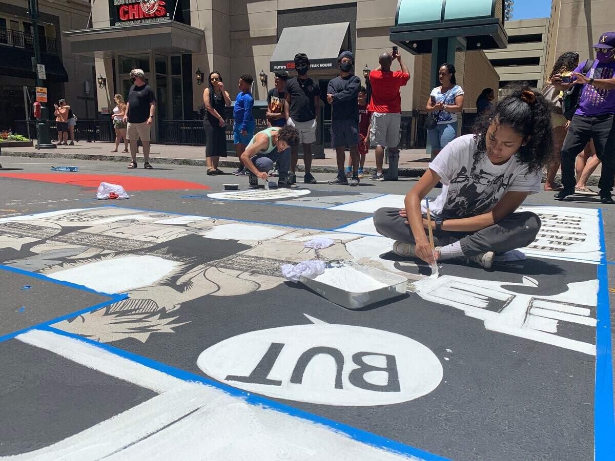 Kiana Mui repaired her letter on the Black Lives Matter mural on Tryon Street in uptown Charlotte after it was defaced by tire tracks.
