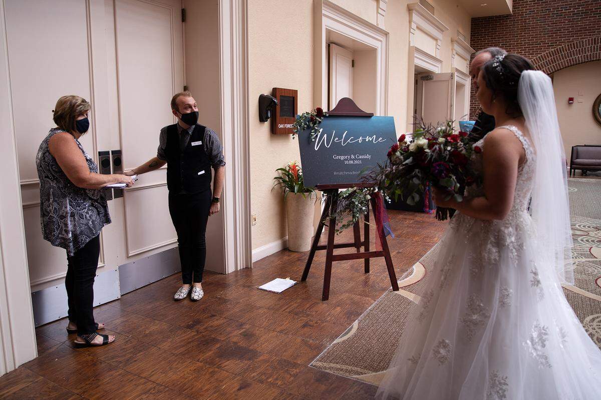 Michelle Jones and Trent Crumpler open the doors for bride Cassidy Taylor to walk down the aisle at the Sheraton Raleigh Hotel.