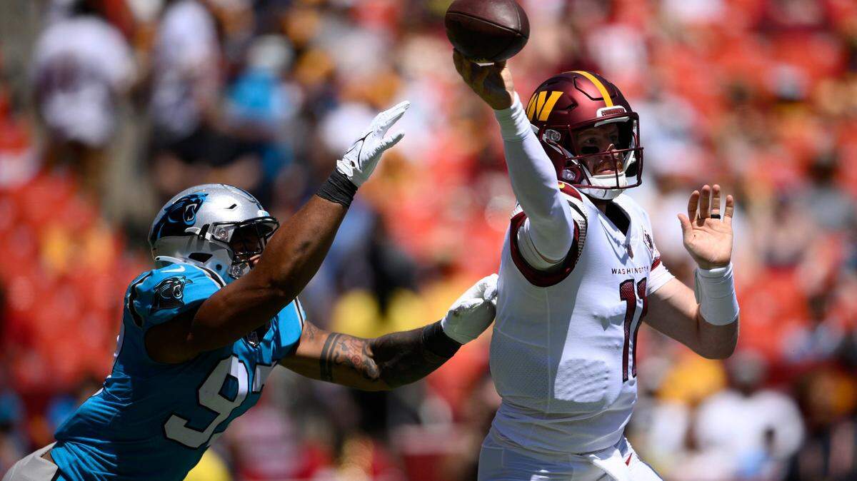 Carolina Panthers defensive end Yetur Gross-Matos, left, pressures Washington Commanders quarterback Carson Wentz, right, during the first half of a preseason NFL football game, Saturday, Aug. 13, 2022, in Landover, Md. (AP Photo/Nick Wass)