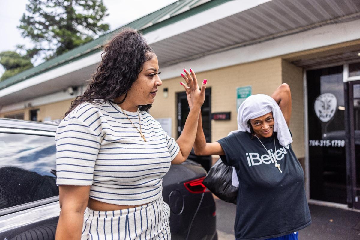 Terica Carter, left, gives a visitor a high five at Hajee House Harm Reduction in Charlotte on July 17.