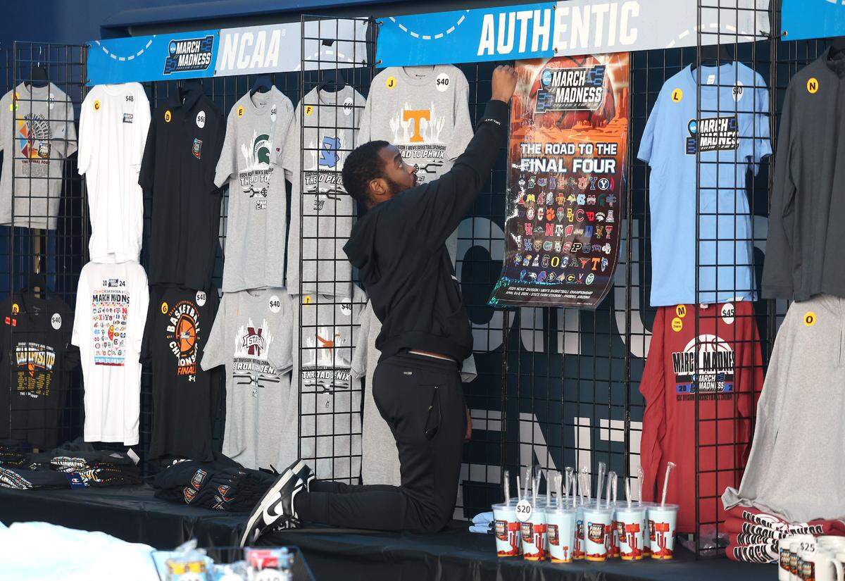 Kamoni McHarris with Hornets Entertainment finishes hanging merchandise in a souvenir stand for the 2024 NCAA Men’s Basketball First/Second Rounds at Spectrum Center in Charlotte, NC on Wednesday, March 20, 2024. Games for the tournament begin on Thursday, March 21, 2024 and conclude on Saturday, March 23, 2024.