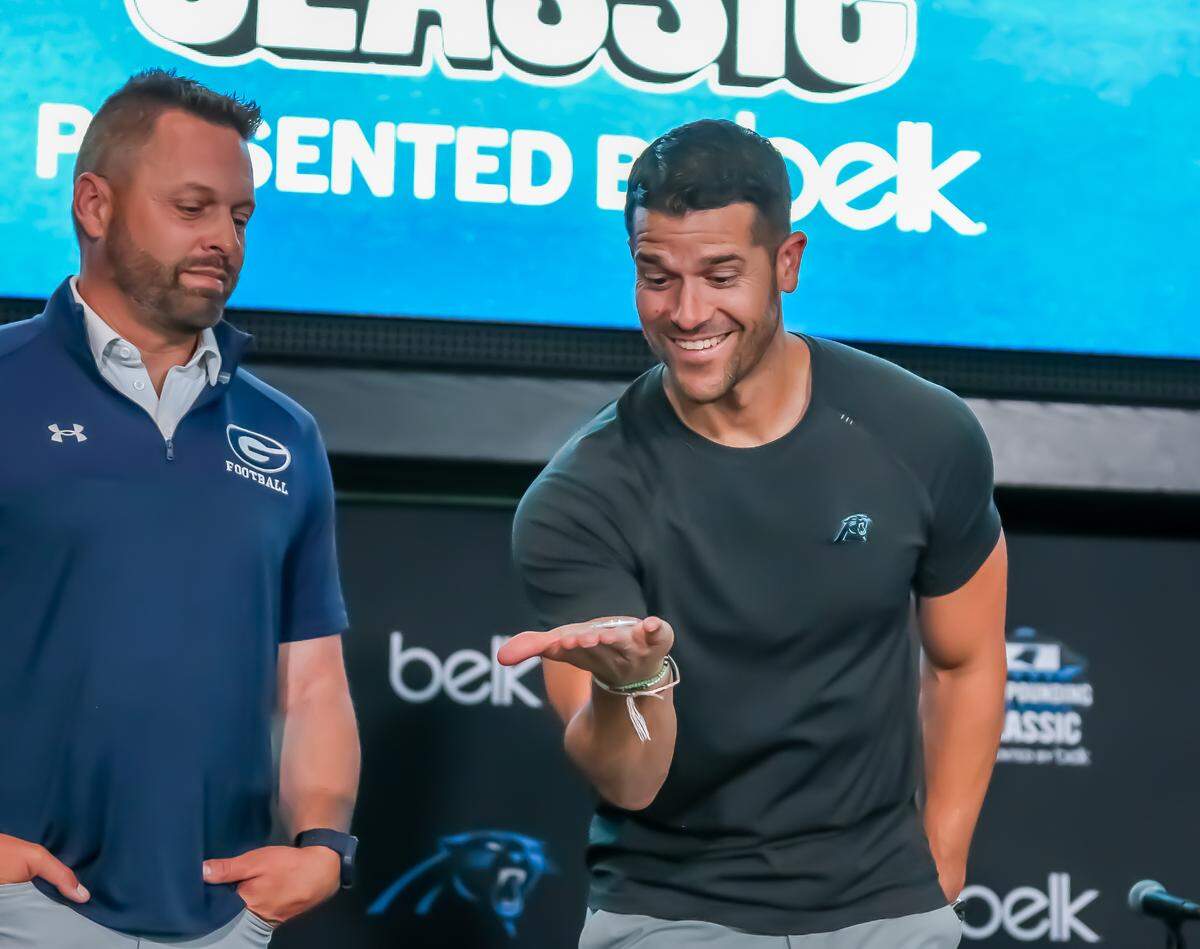 Greensboro Grimsley coach Darryl Brown watches on as Carolina Panthers’ coach Dave Canales performs a ceremonial coin toss during media day for the Keep Pounding High School Classic Wednesday, May 7, 2025
