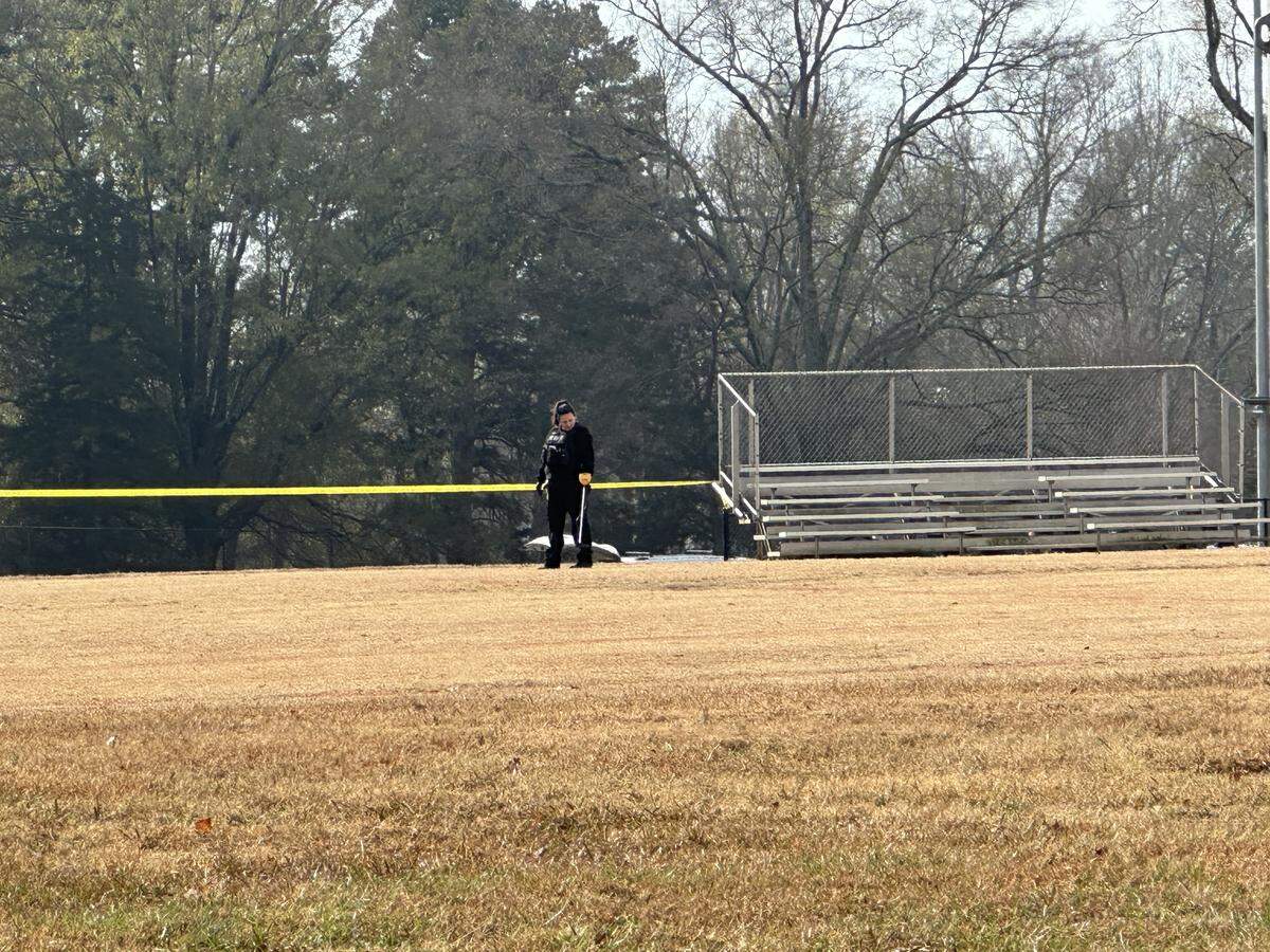 A CMPD officer using what appeared to be a metal detector at the crime scene in the 4800 block of Tuckaseegee Road.