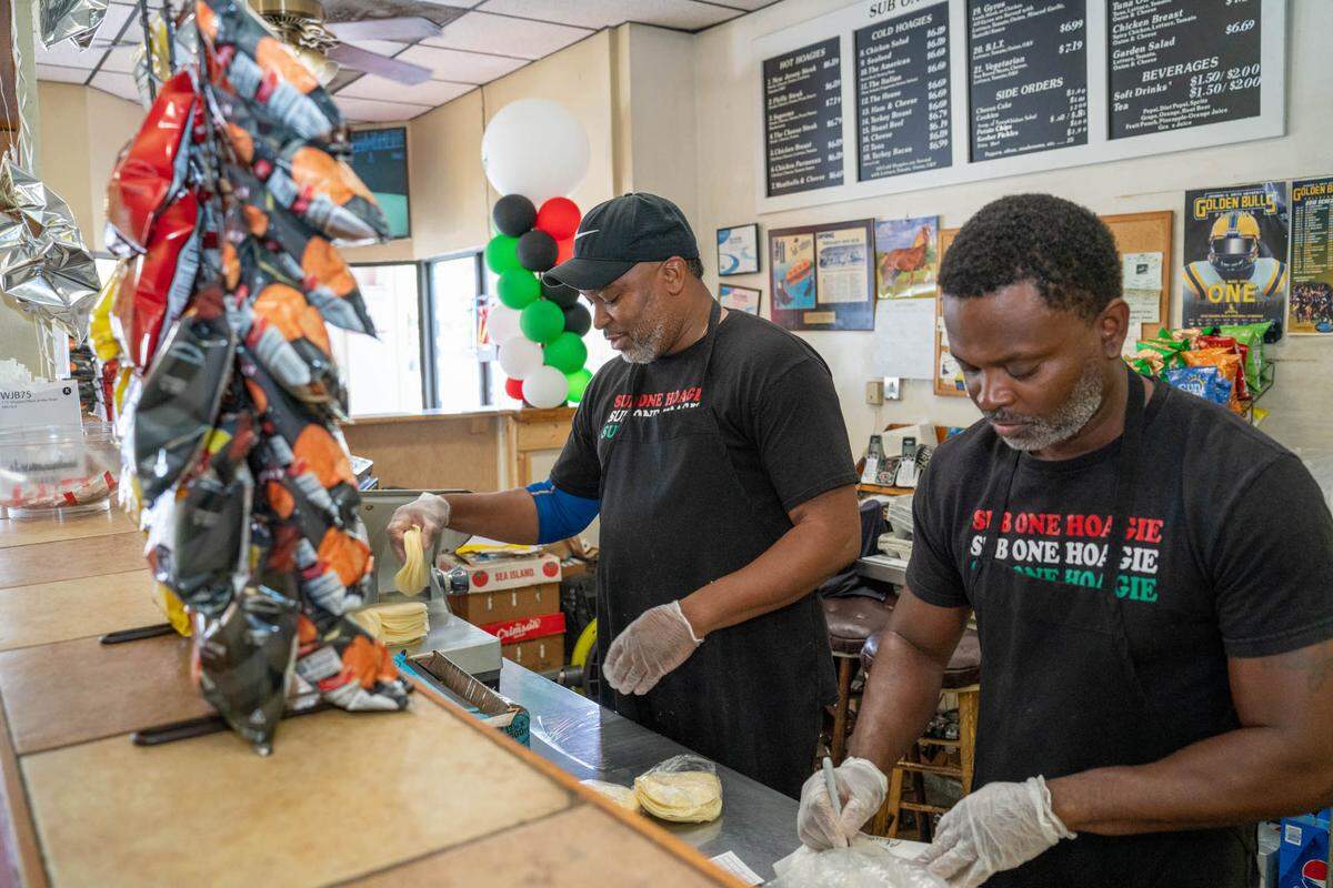 Aaron Jones cuts cheese slices and works next to his cousin Derek Jones. Aaron has been working at Sub One Hoagie House for 25 years.