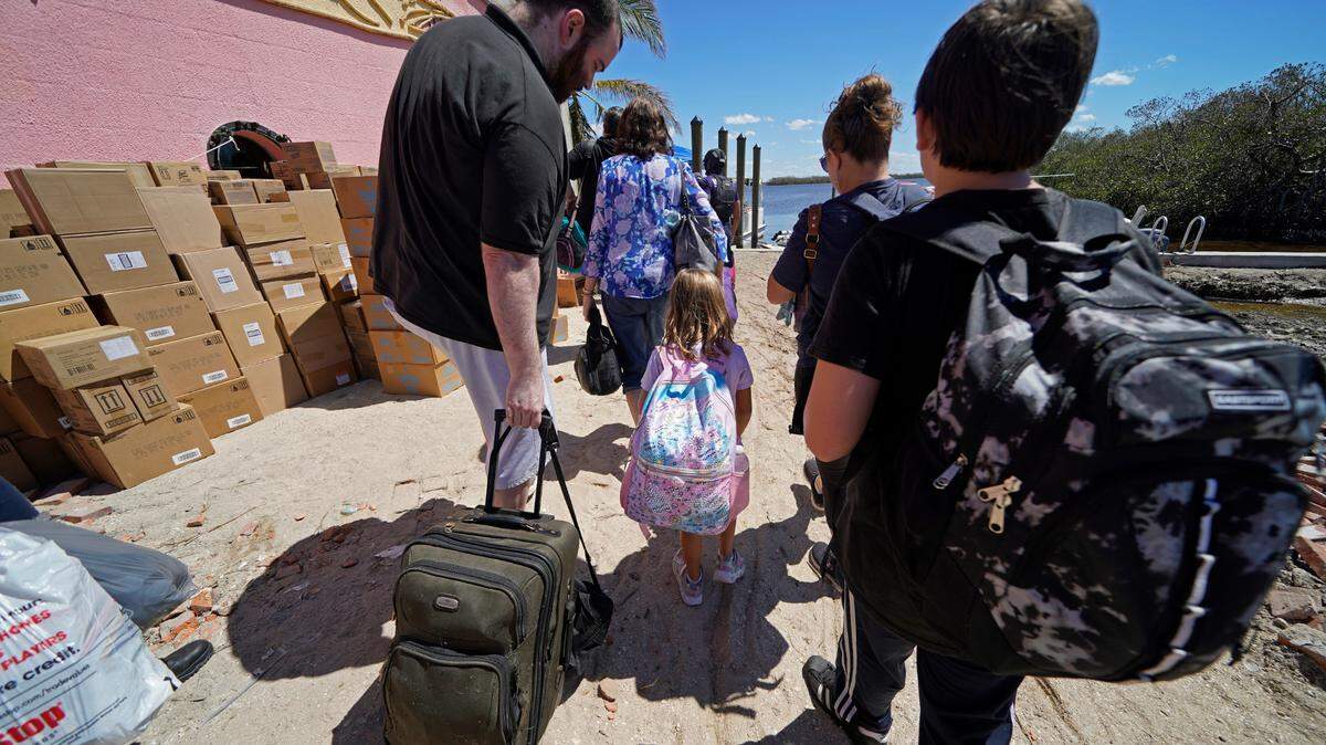 A family that rode out Hurricane Ian arrives at a dock to be evacuated by boat from Florida’s Pine Island on Oct. 2, 2022. The only bridge to the island was heavily damaged, so the island can only be reached by boat or air. 