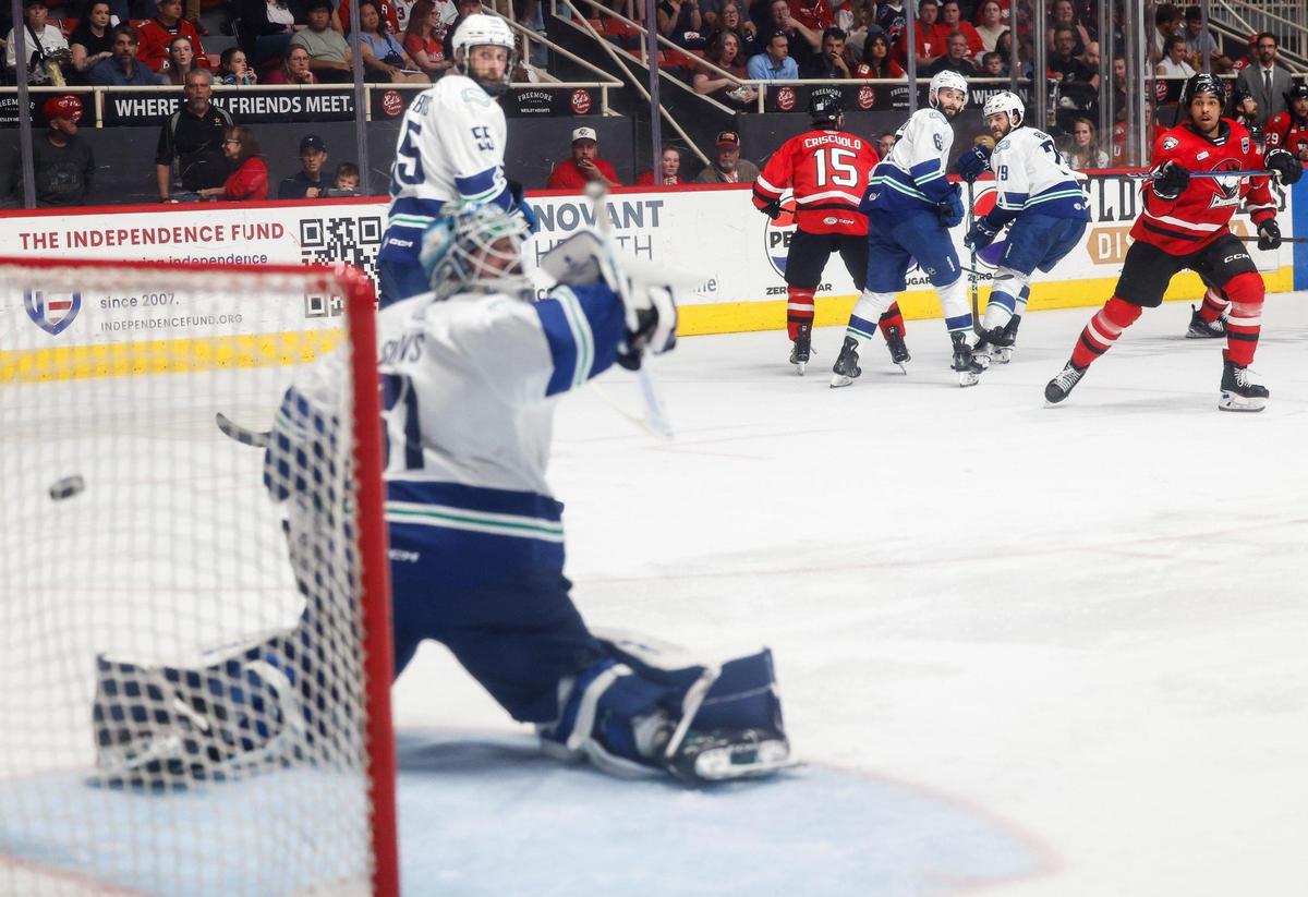 Checkers forward Justin Sourdif, far right, watches the puck fly by Canucks goalie Arturs Šilovs for the third during the Calder Cup Finals at Bojangles Coliseum in Charlotte, NC on Friday, June 13, 2025.