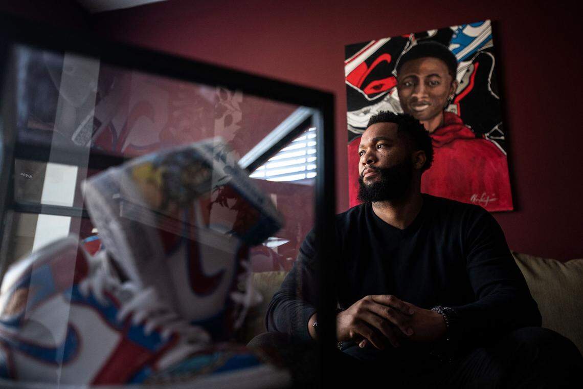 Jeremicus Porter poses with a painting of his son, Justin Porter, as well a pair of sneakers decorated in his honor. “It’s something I’ll never get over,’” Jeremicus Porter said of the high-speed crash that killed his son.