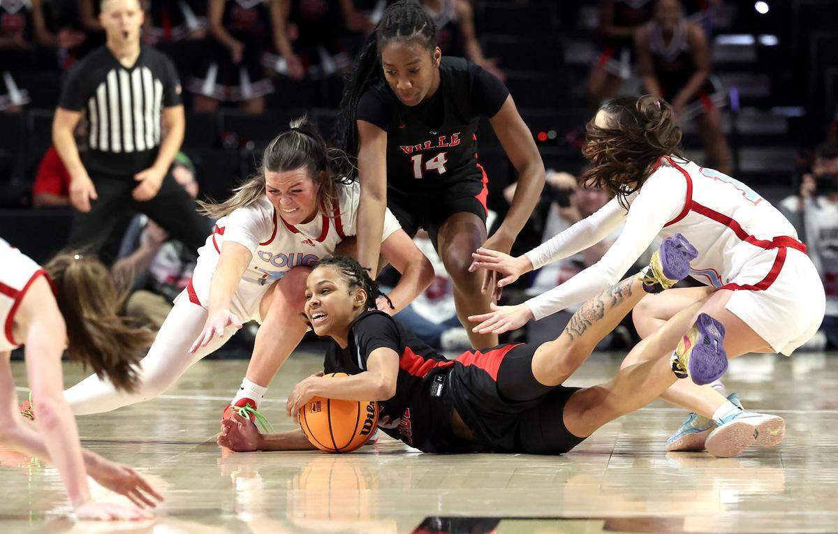 Rolesville’s Caitlyn Jones, center, grabs control of a loose ball as the Charlotte Catholic defense looks to knock the ball away during second-half action in the NCHSAA 4A State Championship at Lawrence Joel Veterans Memorial Coliseum on Saturday, March 16, 2024. Rolesville defeated Catholic 65-58.