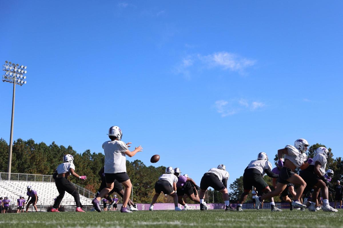 Jack Ludwick (center), senior captain, snaps the ball to quarterback Will Ryland (front), at Ardrey Kell High School on October 25, 2023.