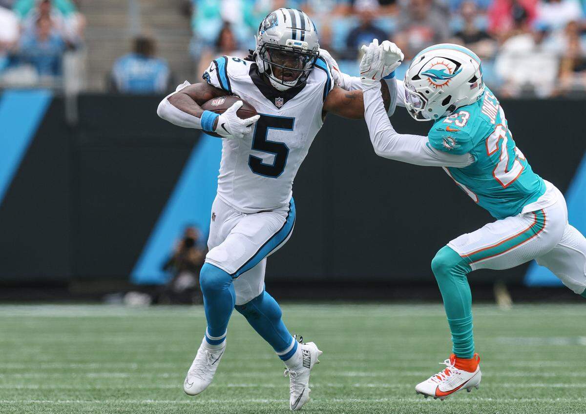 Panthers runningback Rico Dowdle, left, fights off Dolphins cornerback Jack Jones as he runs the ball during the game at Bank of America Stadium in Charlotte, NC on Sunday, October 5, 2025.