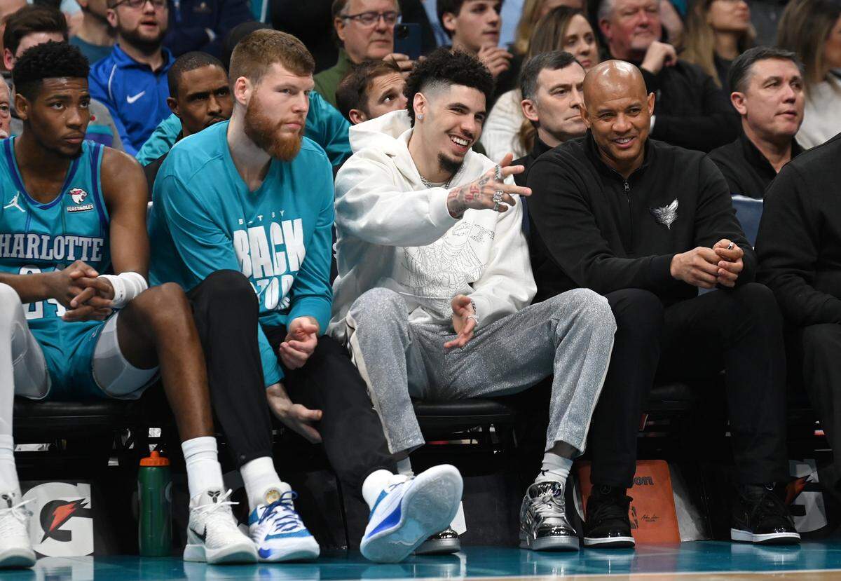 Injured Charlotte Hornets guard LaMelo Ball, center, smiles as he points out to the lane during first half action against the Milwaukee Bucks at Spectrum Center in Charlotte, NC on Thursday, February 29, 2024.